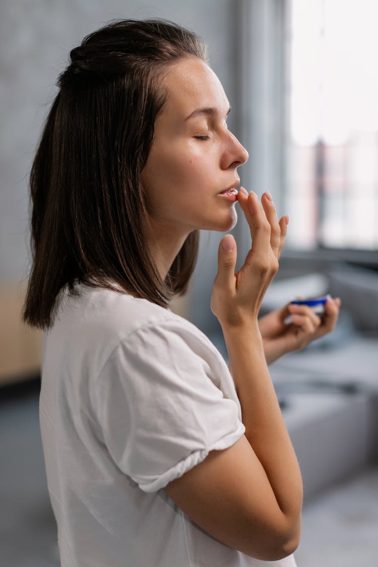 Side View Of A Woman Applying Balm