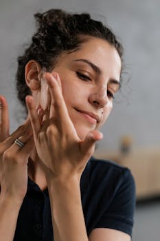 Close-up of a woman applying skincare product to her face, emphasizing healthy skin and care routine.