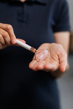 Hands holding a rose quartz face roller, showcasing its sleek design and beauty-enhancing use.
