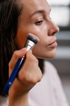 Close-up of a woman gently applying makeup with a brush, highlighting cosmetics application.