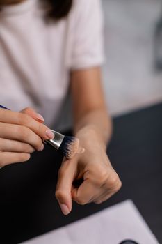 Detailed close-up of using a makeup brush on hand.