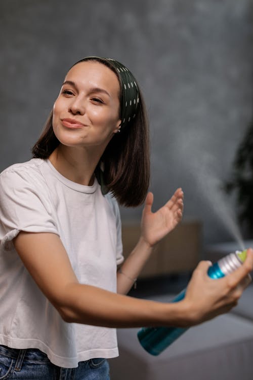 Hairspray bottle spraying onto styled hair. 