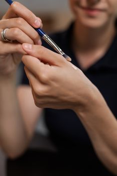 Close-up of woman applying makeup with a brush on hand indoors.