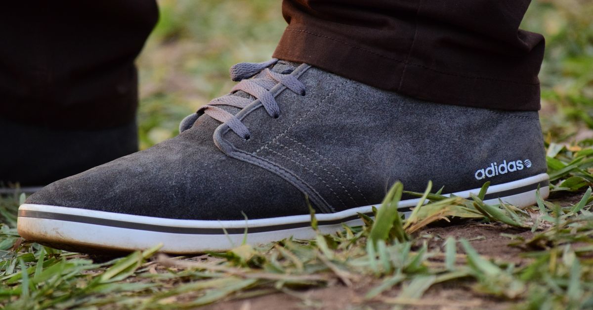 Detailed close-up of a suede Adidas shoe on grass, perfect for fashion and lifestyle themes.