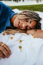 Woman in Blue Denim Jacket Lying on White Bed With White Daisy Flowers