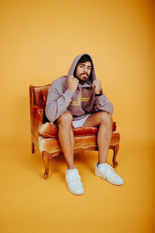 A Man Wearing Hoodie while Sitting on Chair