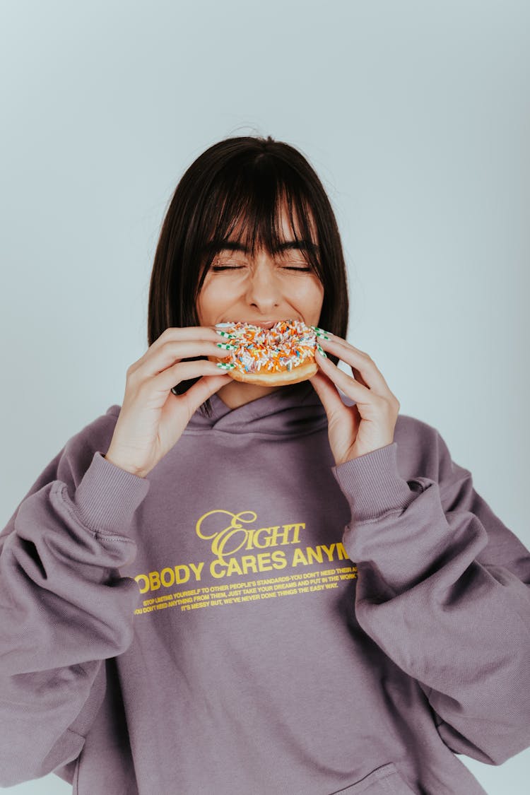 Woman Wearing Hoodie Sweater Eating A Donut 