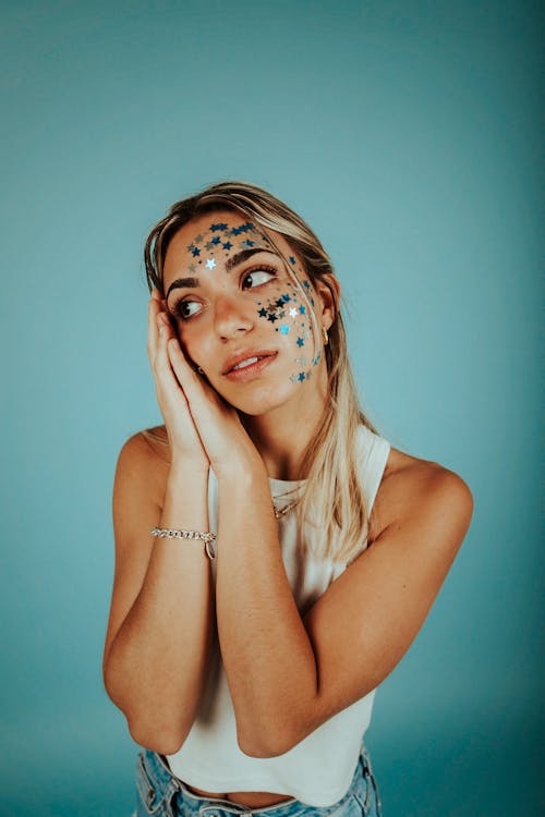Free Woman in White Tank Top With Sparling Stars on Face and Hands Beside Face Stock Photo