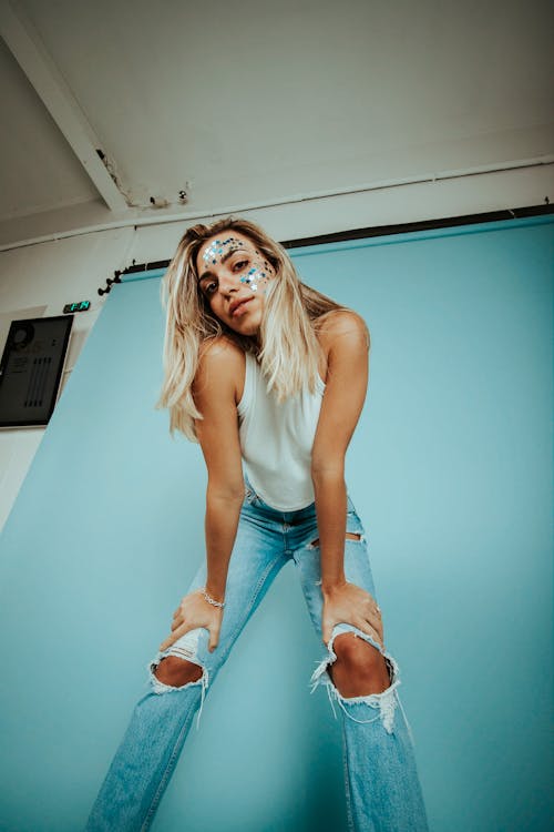 Woman in White Tank Top and Blue Denim Jeans with Glitter on Face