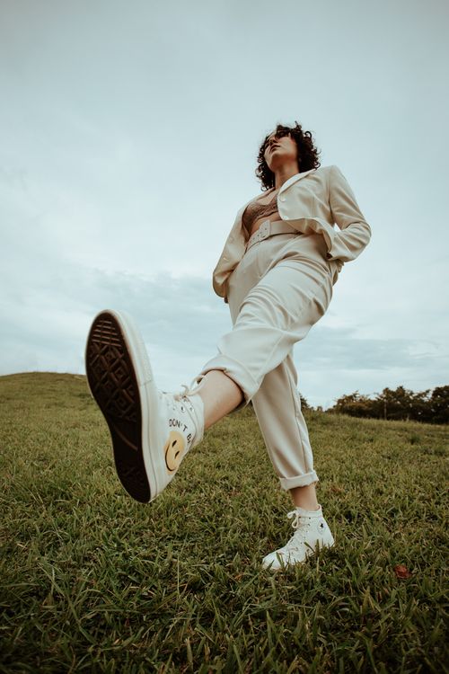 Free Fashionable woman in beige blazer posing outdoors on grass, low angle shot. Stock Photo