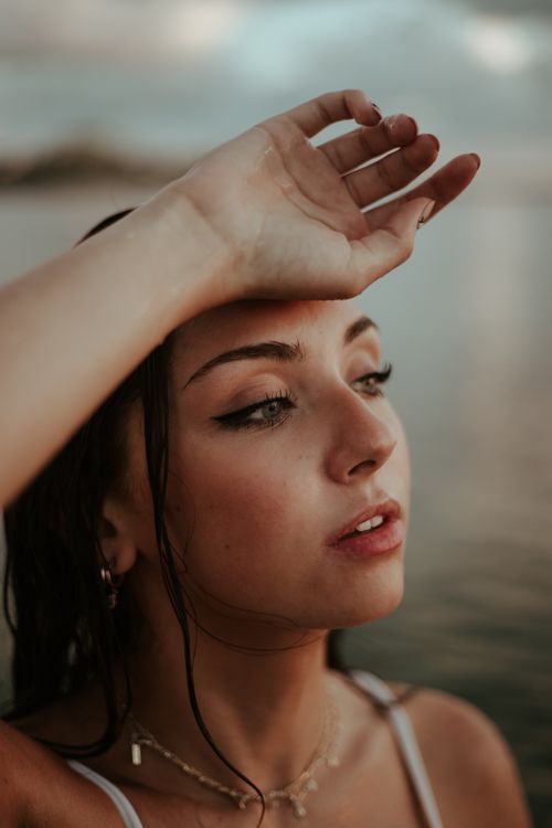 Free A thoughtful woman gazes into the distance by the sea during twilight, creating a serene atmosphere. Stock Photo