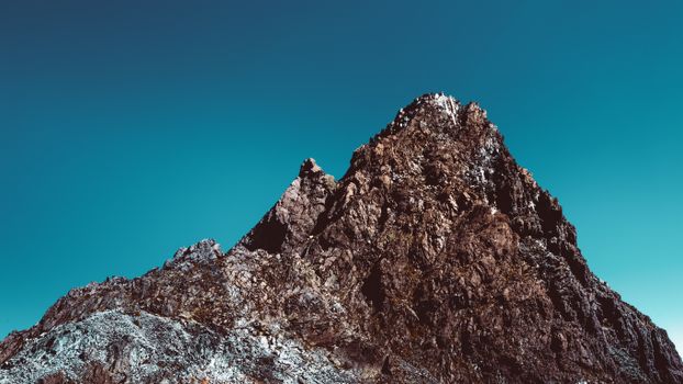 A stunning view of a towering mountain peak against a cloudless blue sky in Japan.