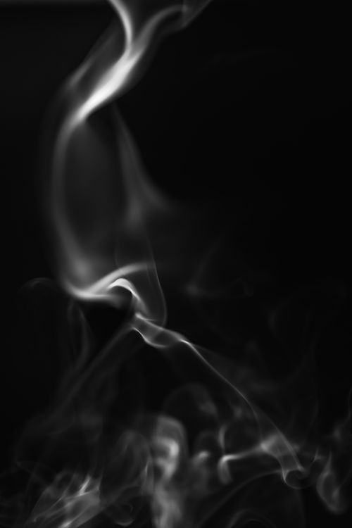 Free Artistic black and white image of swirling smoke on a dark background with a mysterious feel. Stock Photo