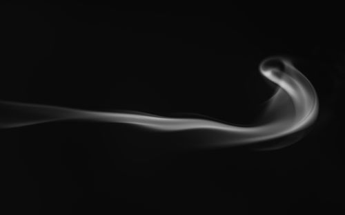 Free A graceful smoke trail with abstract curves on a black background, creating a mysterious effect. Stock Photo