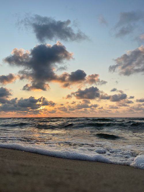 Free Beautiful sunrise over the ocean with waves and clouds, creating a tranquil seascape. Stock Photo