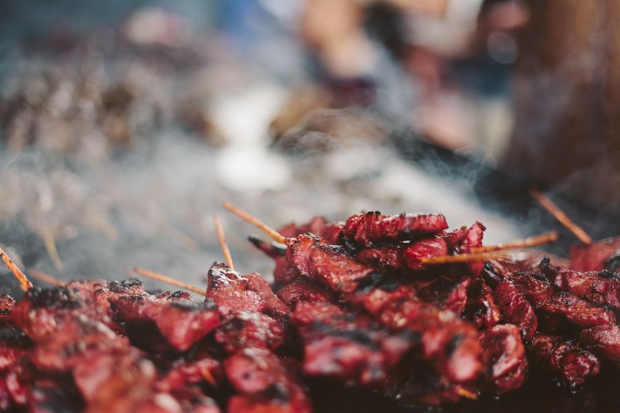 Close-up of meat skewers sizzling on a grill with smoke