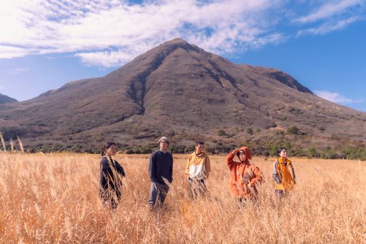 A group of friends standing in a scenic mountain field during daytime, enjoying the outdoors.