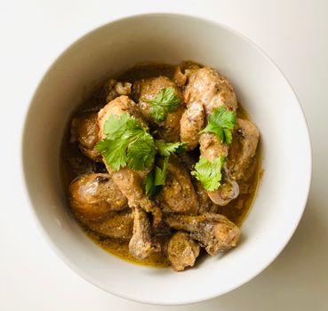 A tempting bowl of chicken curry garnished with fresh cilantro, perfect for Asian cuisine lovers.