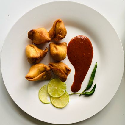 Fried pastry parcels with chilli dip and lime on a white plate, photo by I Own My Food Art on Pexels
