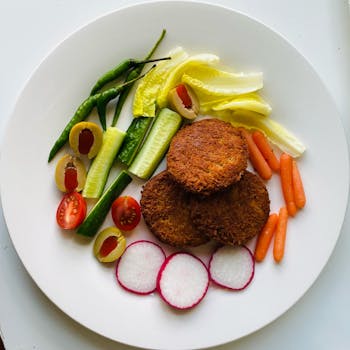 A vibrant vegetarian platter featuring falafel and a variety of fresh vegetables on a white plate.