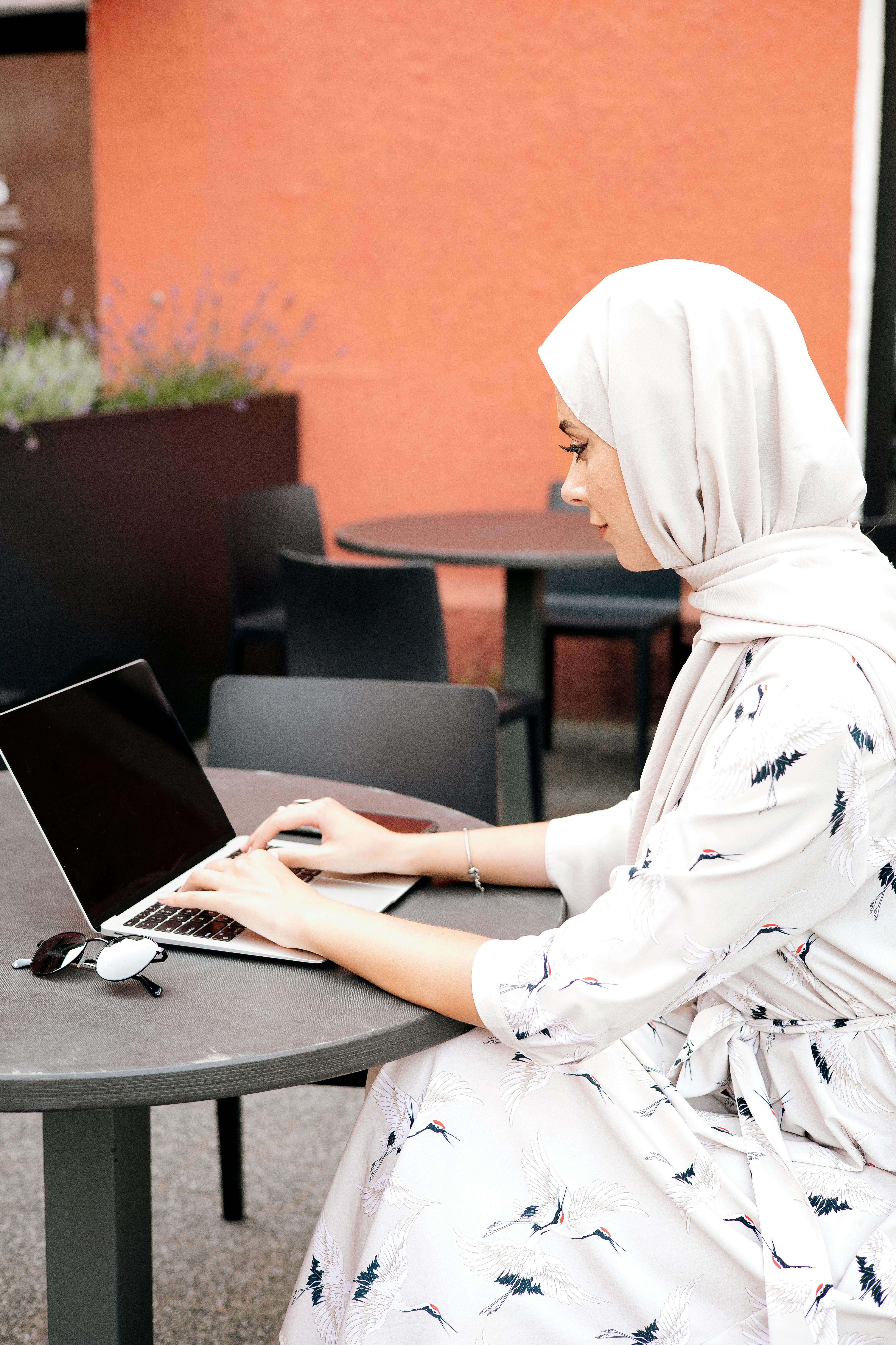 woman in white dress using a laptop