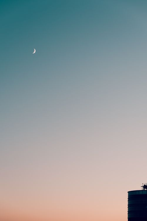 Free Minimalist cityscape with crescent moon in a clear sky during dusk. Perfect for serene and modern themes. Stock Photo