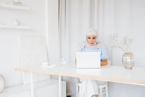 A Woman with Gray Hijab Using a Laptop while Sitting