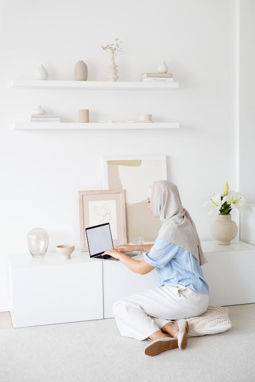 Woman in White Hijab Sitting on Floor while Using Laptop