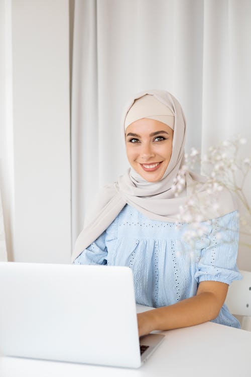 Woman in Beige Hijab and Blue Shirt Using Laptop