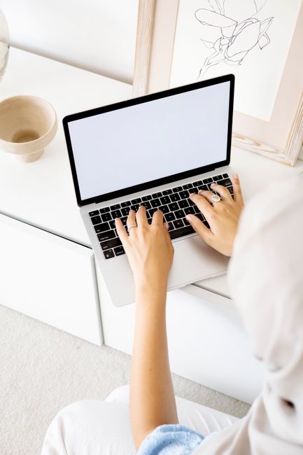 A woman works on a laptop in a bright, minimalist space, highlighting remote work lifestyle.