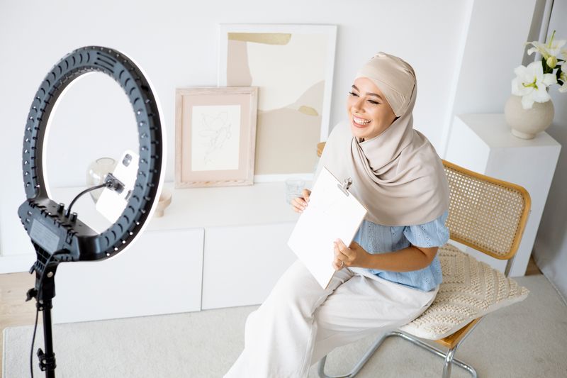 Malaysian content creator in hijab recording with a ring light