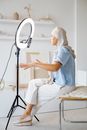 Woman in Blue Shirt and White Pants Sitting on White Chair