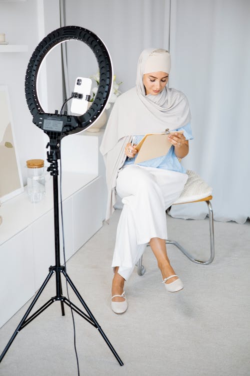 
A Woman Wearing a Hijab Looking at a Clipboard