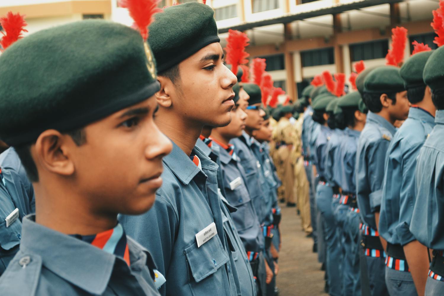 Young Indian NCC cadets in uniform stand at attention during an outdoor parade ceremony.