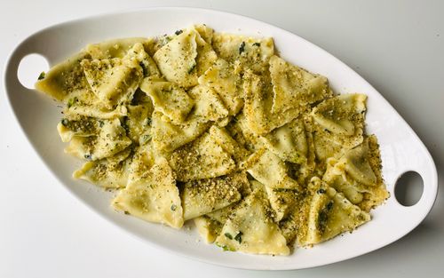 Free Close-up of homemade pesto pasta on a white ceramic plate, garnished with herbs. Stock Photo