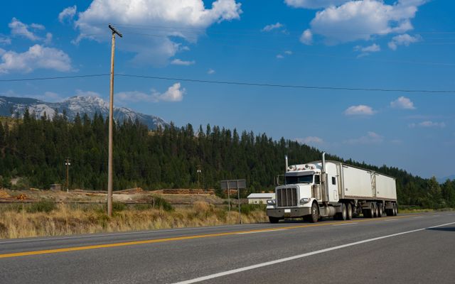 Semi-truck hauling freight on scenic BC highway with Canadian mountains - EquipEASE transportation financing