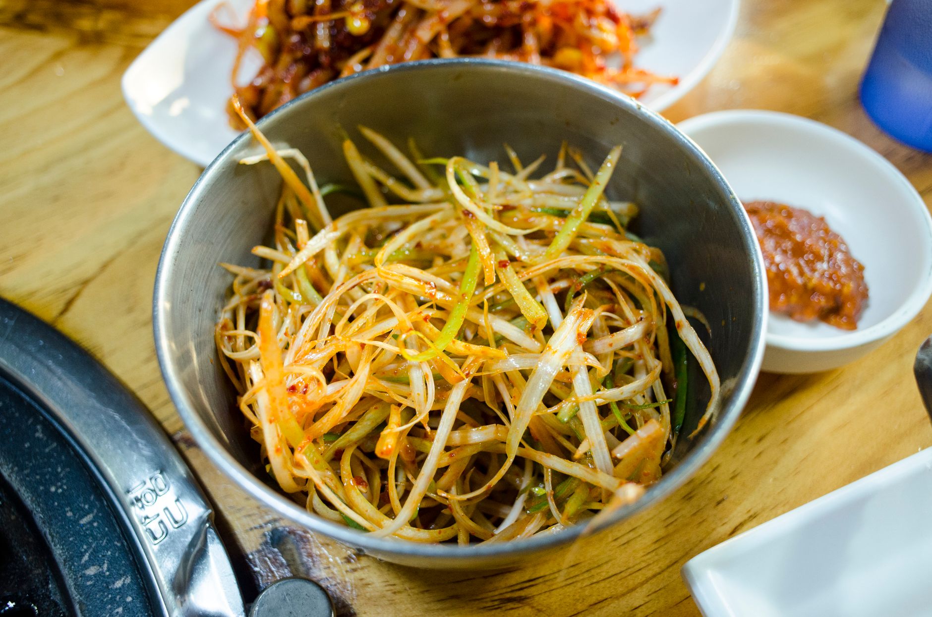 Close-up of spicy Korean green onion salad served as a side dish in a metal bowl.