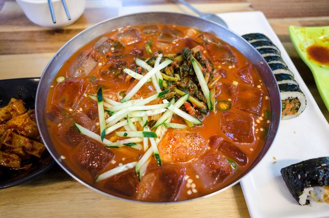 Freshly prepared Korean cold noodle dish served with side dishes, perfect for a summer feast.