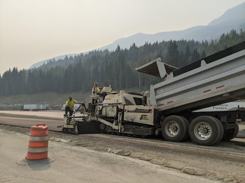 People Working on a Heavy Machinery in the Road