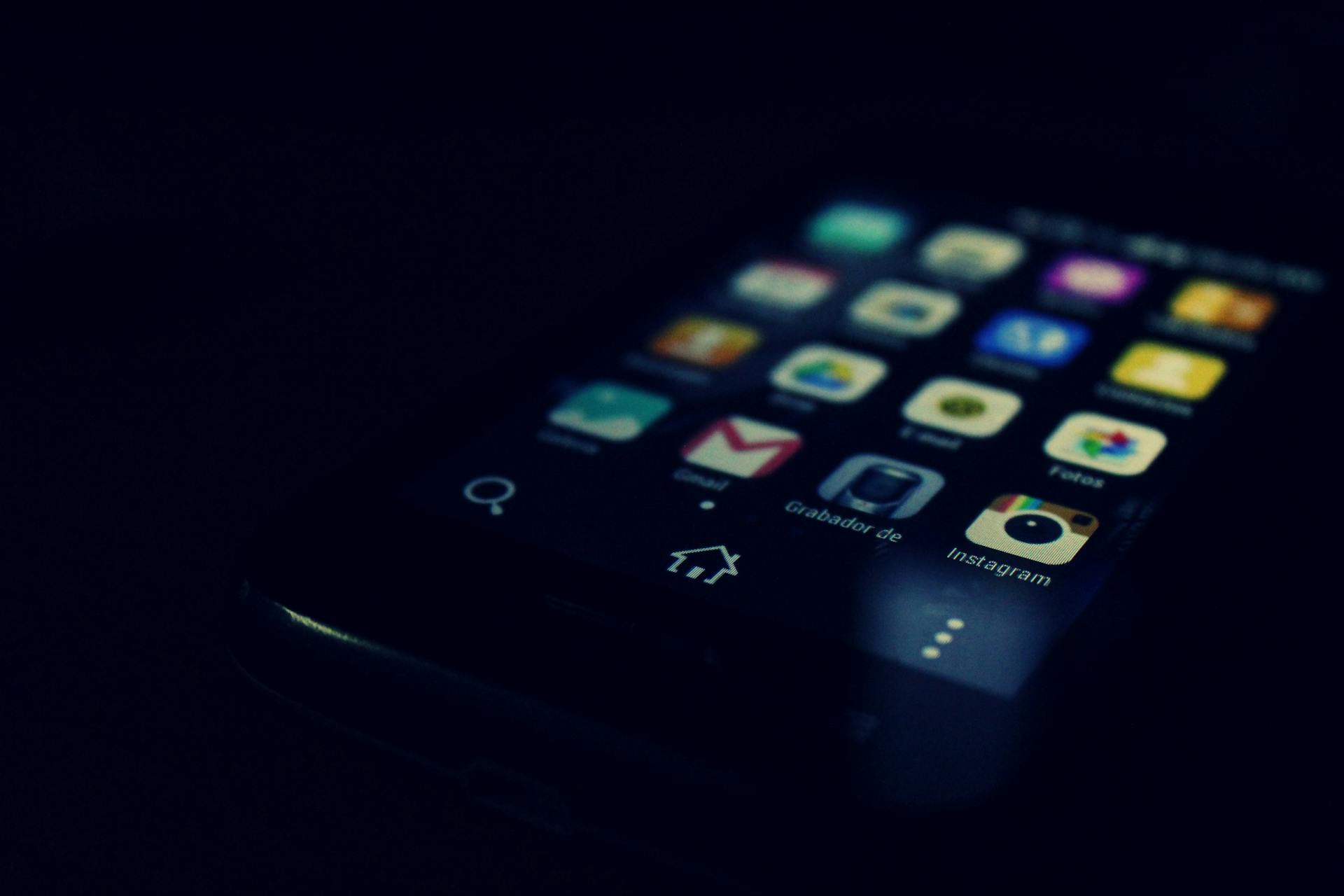 Dark-themed close-up of a smartphone screen highlighting various apps and touchscreen technology.