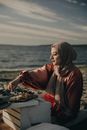 Woman in Brown Hijab Sitting on White Textile on Beach