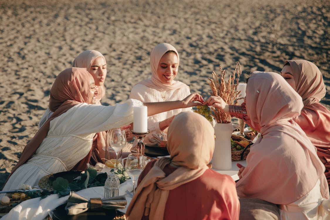 Free Women in Hijab Having a Picnic on the Beach Stock Photo
