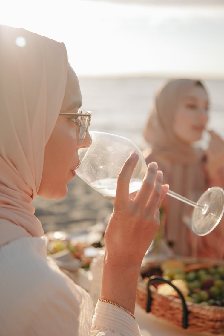 Woman In Hijab Drinking Water From A Glass During Picnic On The Beach