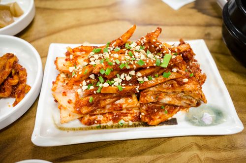 Free Delicious spicy kimchi served with green onions and nuts on a ceramic plate. Stock Photo