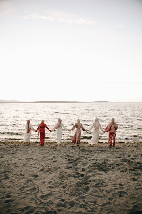 Six Women Holding Hands While Standing on the Beach