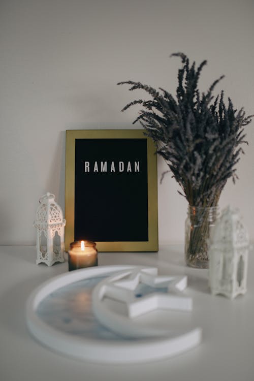 A Ramadan Word on a Picture Frame Beside Dried Leaves and a Candle Light