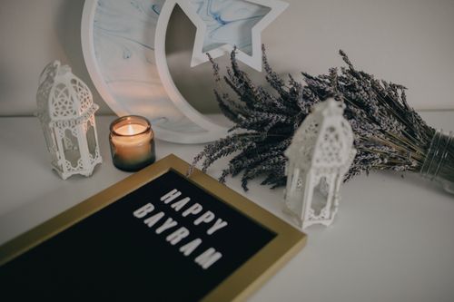 Free Festive Eid decoration with a Happy Bayram sign, lanterns, and lavender on a table. Stock Photo