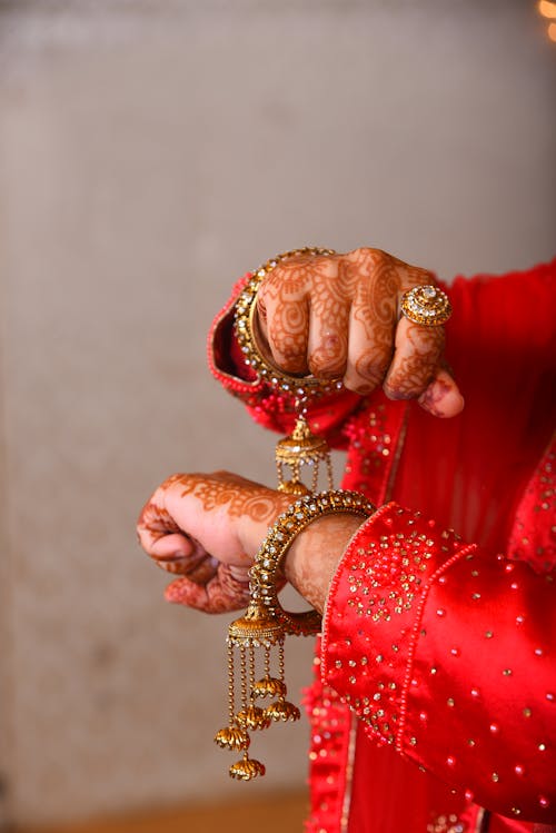 Closeup of a Woman Wearing Red Traditional Clothing, Bracelets, and Mehendi Paint