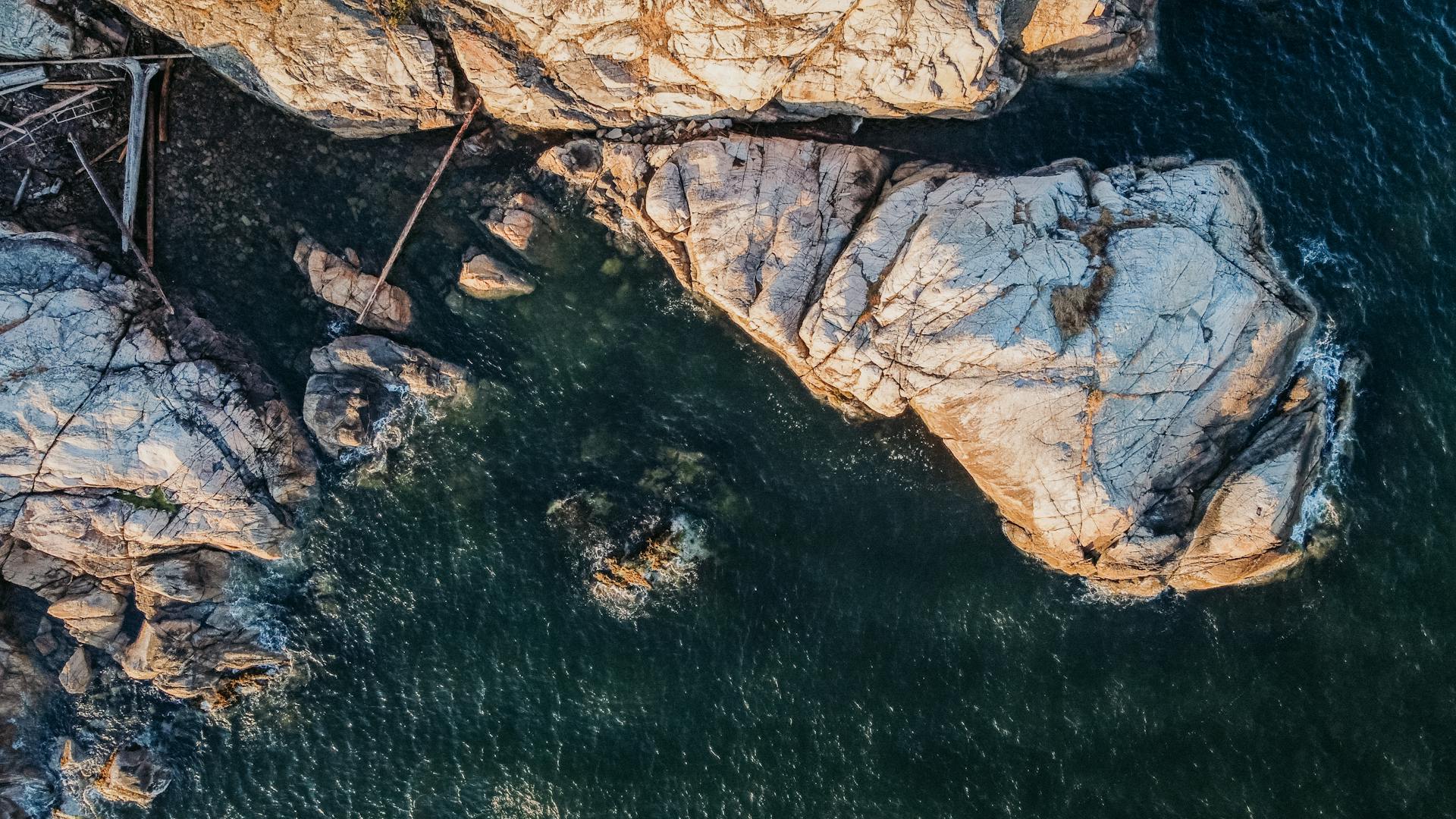 Drone shot of rocky coastline and ocean in West Vancouver, capturing natural beauty and rugged terrain.