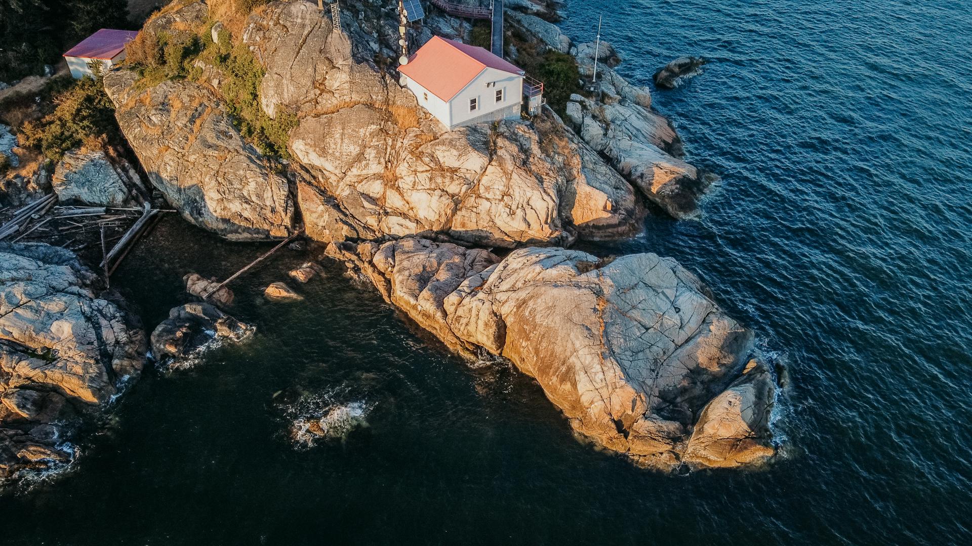 Aerial view of a lighthouse perched on rocky cliffs along the ocean in West Vancouver, BC, Canada.